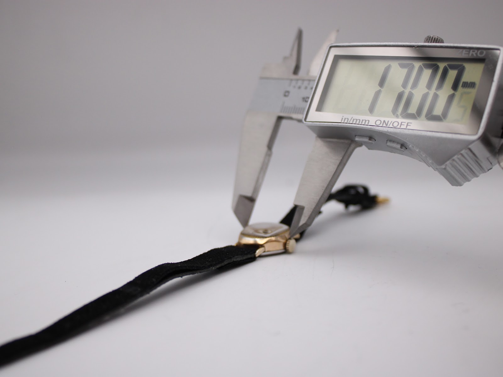 Digital caliper measuring the watch case, displaying a precise diameter of 17.00 mm.