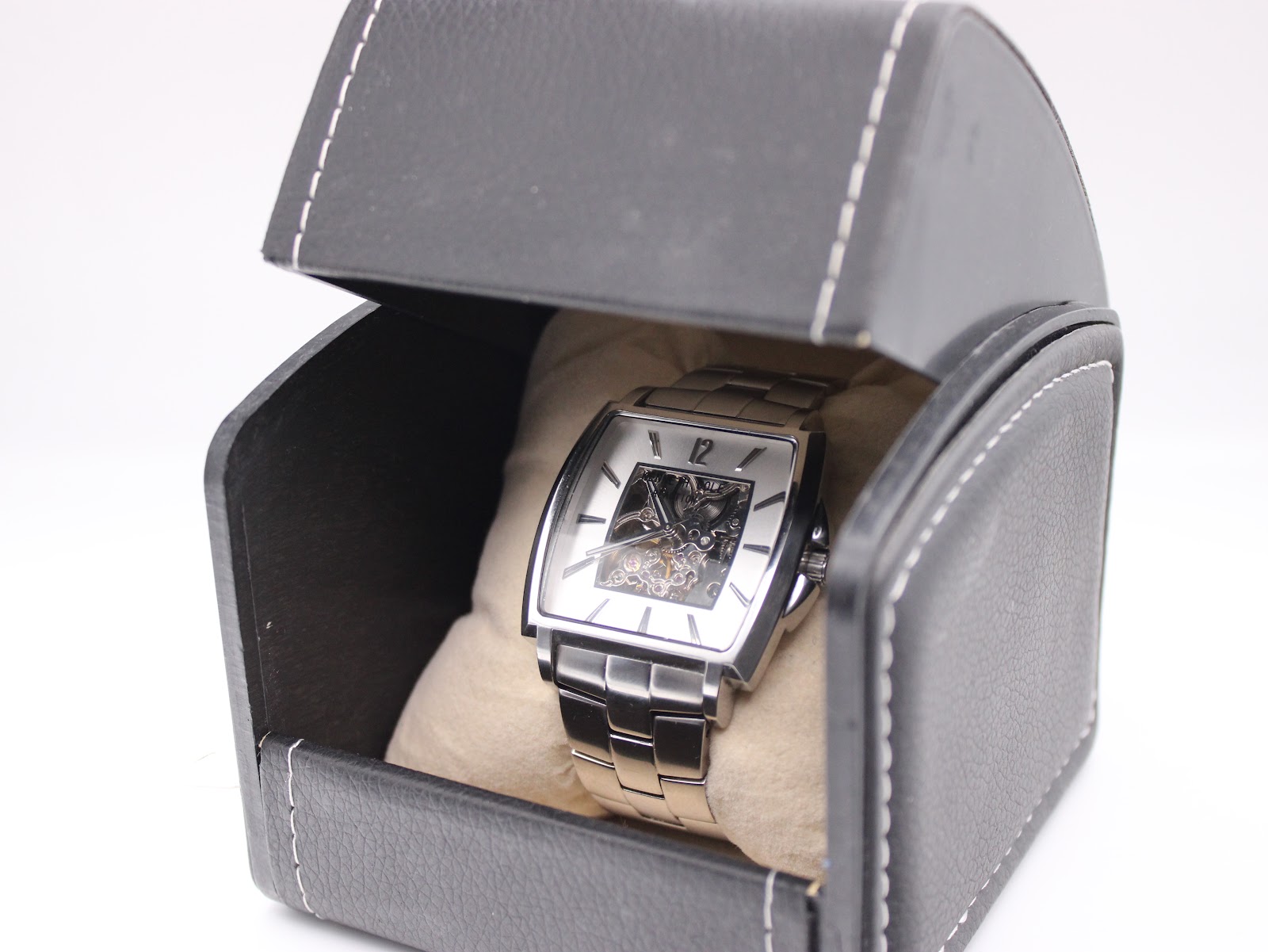 The Kenneth Cole watch nestled inside a black faux leather travel box with a cream interior cushion.