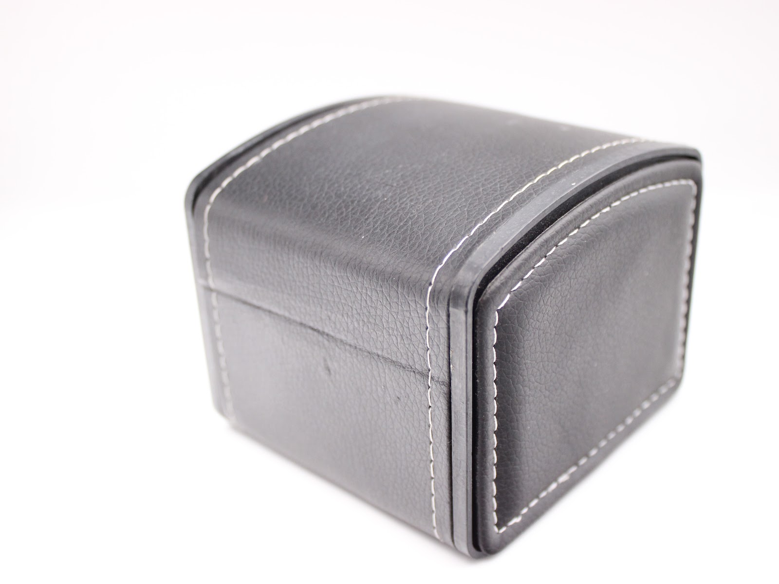 Exterior view of the black faux leather travel box with distinctive white stitching on the edges.