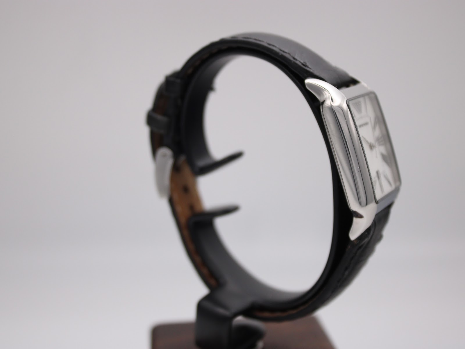 Opposite side profile view of the Emporio Armani AR-0413 watch on a stand, showing the sleek case design and strap.