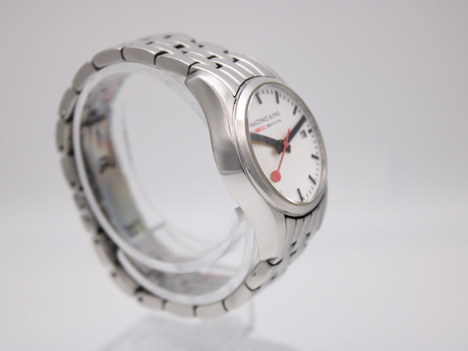 Angled side view of the Mondaine watch, highlighting the case profile and the bracelet's link construction.