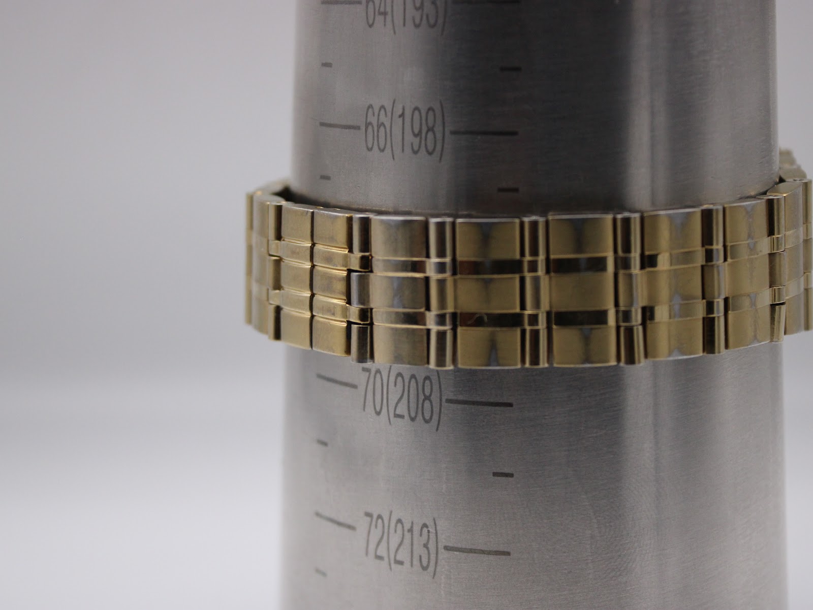 Close-up of the gold-tone bracelet on a wrist sizing cone, indicating a circumference of approximately 19.8 cm.