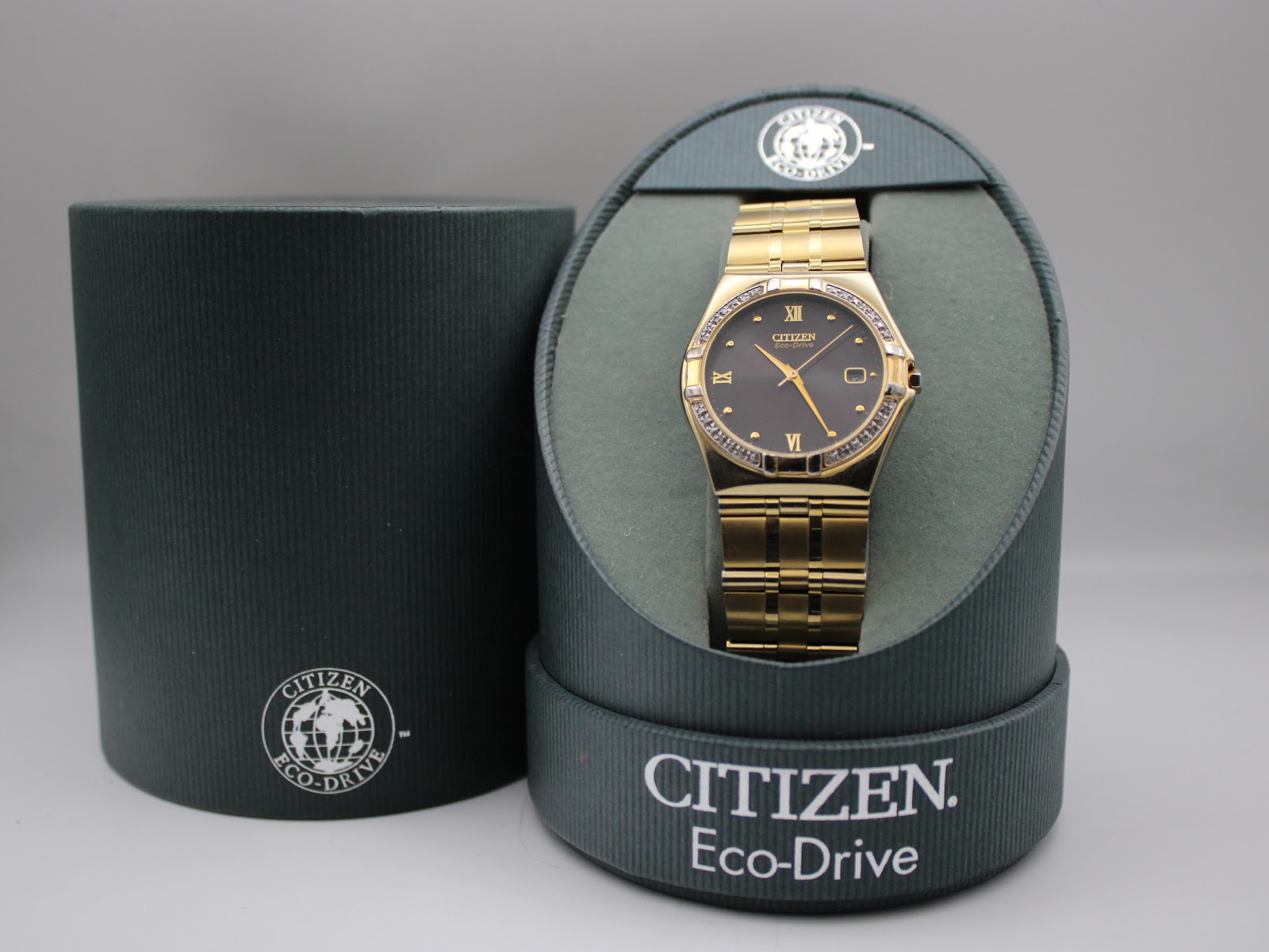 The Citizen Eco-Drive watch displayed in its original green cylindrical presentation box.