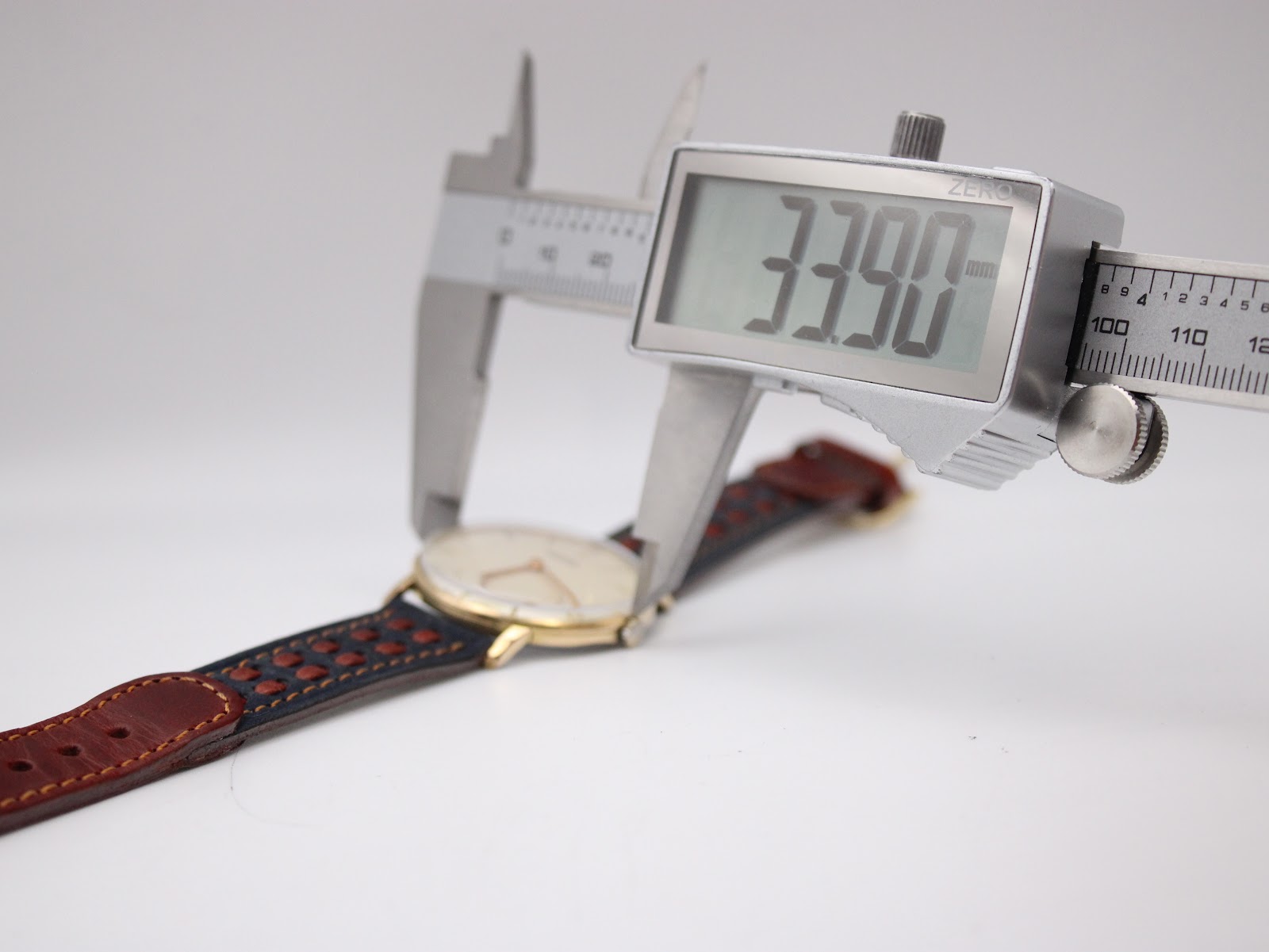 A digital caliper measuring the case diameter of the Roamer watch, displaying an exact measurement of 33.90mm.