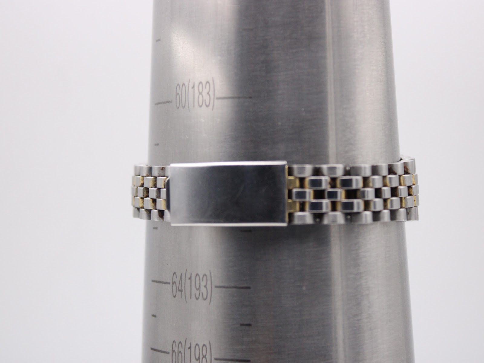 Close-up of the watch bracelet clasp on a ring sizing mandrel, showing the two-tone links and the plain steel clasp.