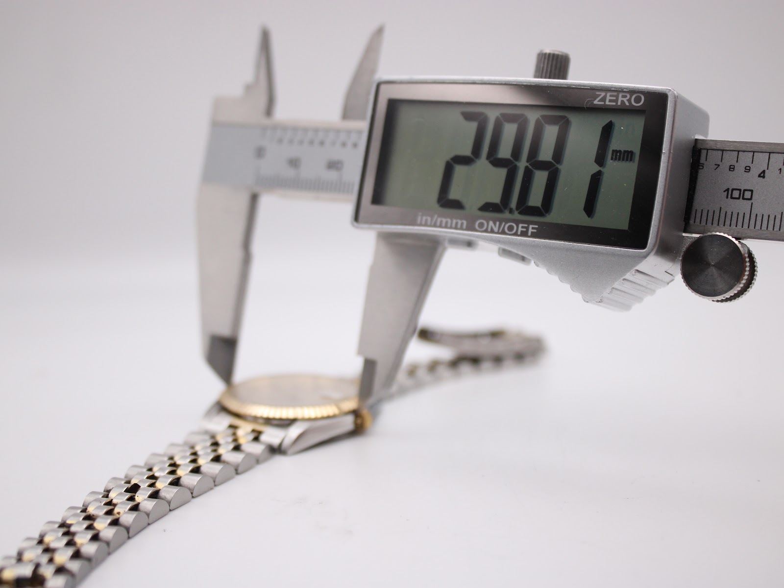 Close-up of the watch case being measured by a digital caliper, displaying a precise diameter of 29.81 mm.