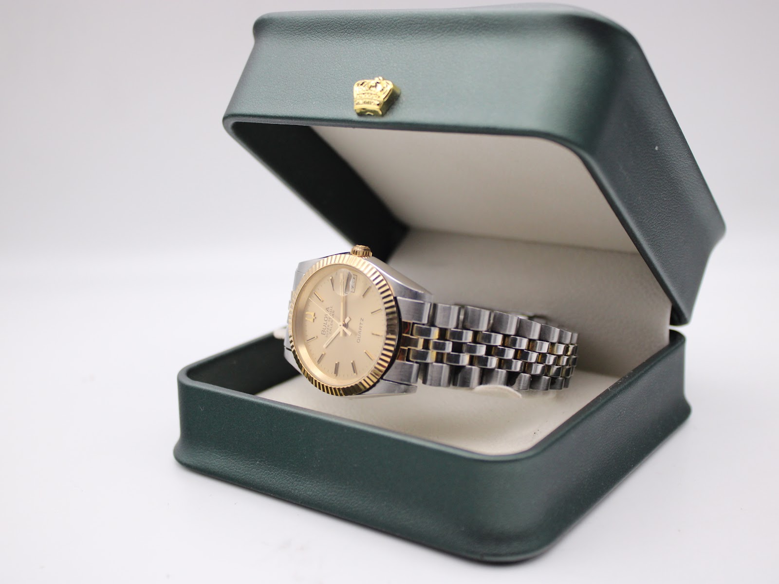 The Bulova Super Seville watch sitting in an open dark green presentation box with a gold crown emblem on the lid.