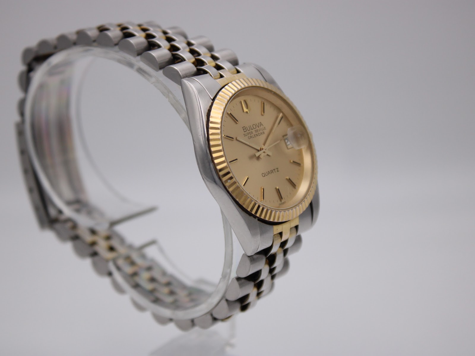 Another angled view of the Bulova Super Seville on a clear watch stand, highlighting the champagne dial and two-tone bracelet.