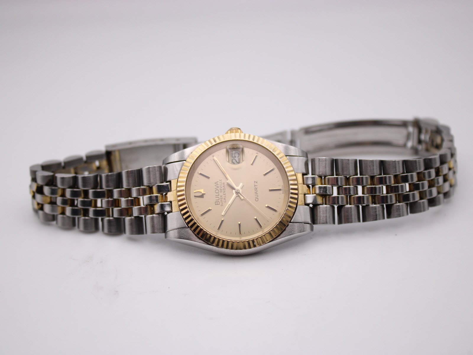 Full front view of the Bulova Super Seville watch with its two-tone bracelet extended on a white surface.