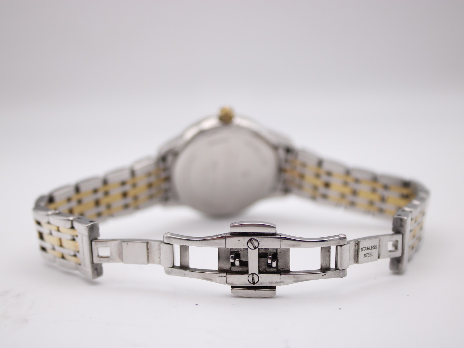 Rear view of the open two-tone bracelet clasp with "stainless steel" marking.