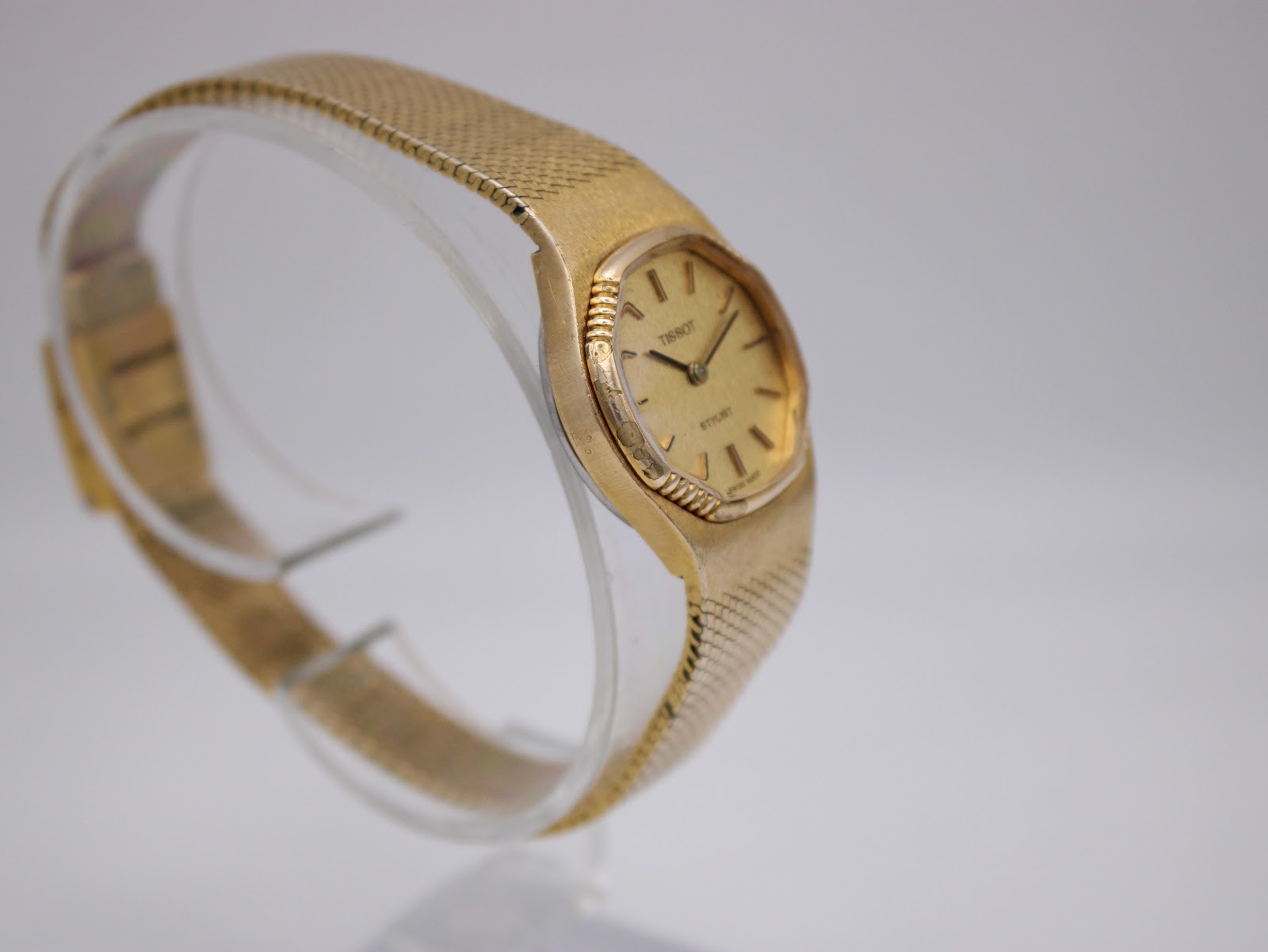 Side-angled view of the gold Tissot Stylist, highlighting the textured case and bracelet.