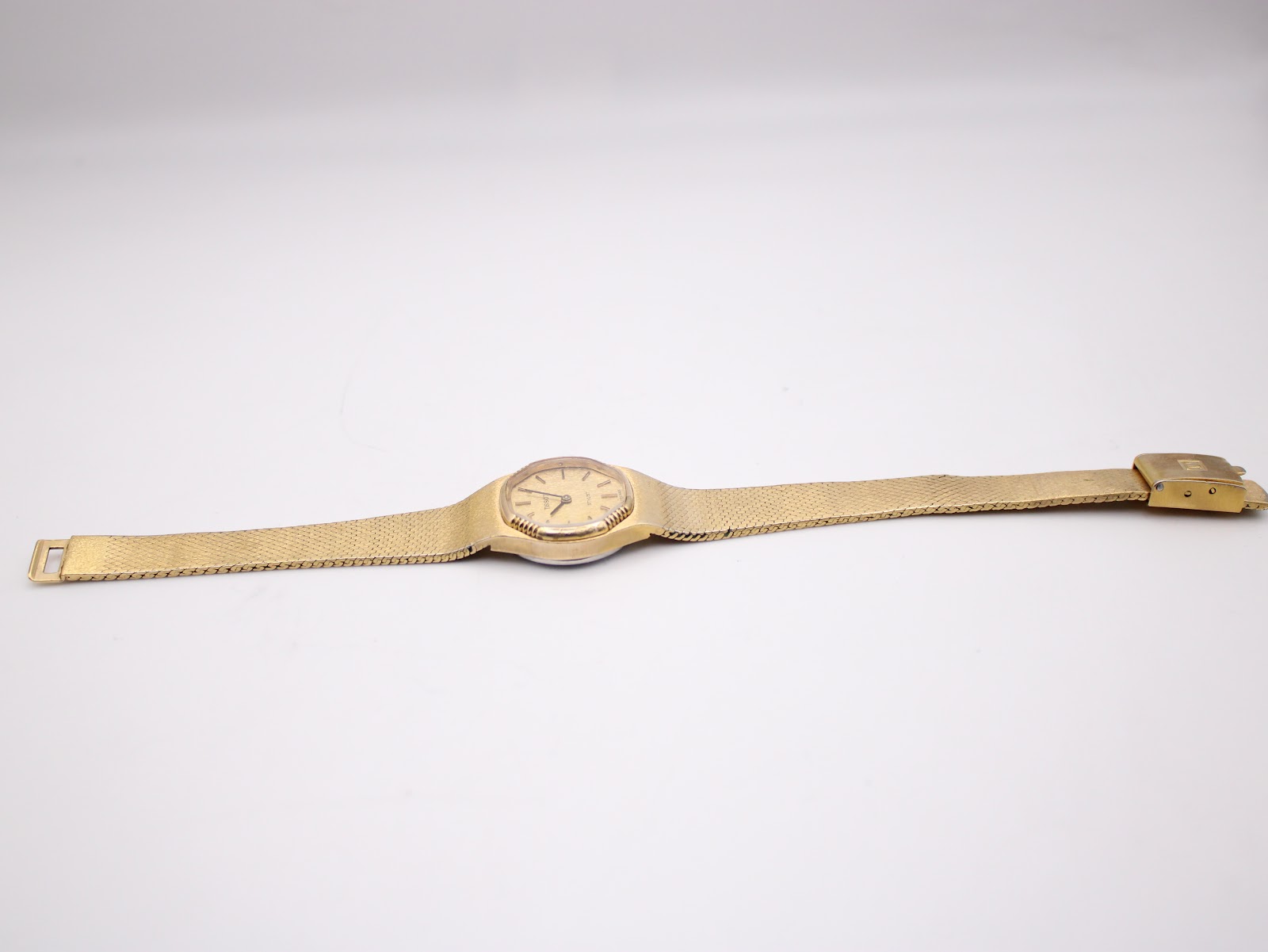 Full length view of the Tissot Stylist watch and integrated bracelet, laid flat on a white background.
