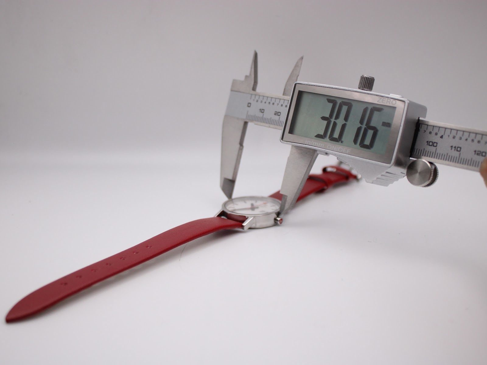 Digital caliper measuring the case diameter of the Mondaine watch, displaying an exact measurement of 30.16mm, confirming the size without crown.