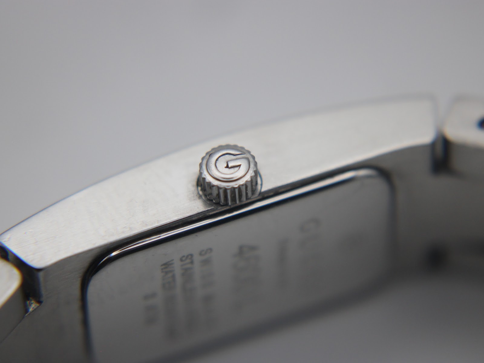 Extreme close-up of the watch crown, featuring the iconic embossed Gucci 'G' logo.