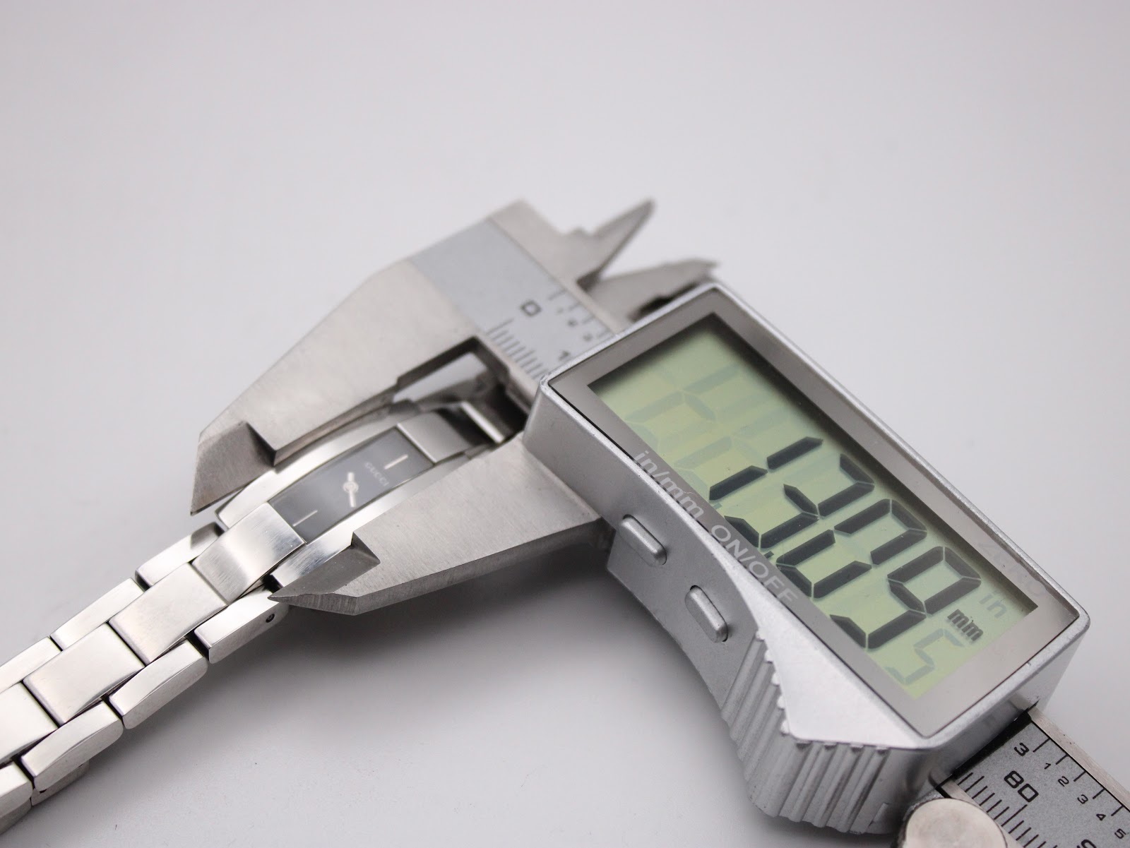 Digital caliper measuring the case width of the Gucci 4600L, displaying an exact measurement of 13.09 mm.