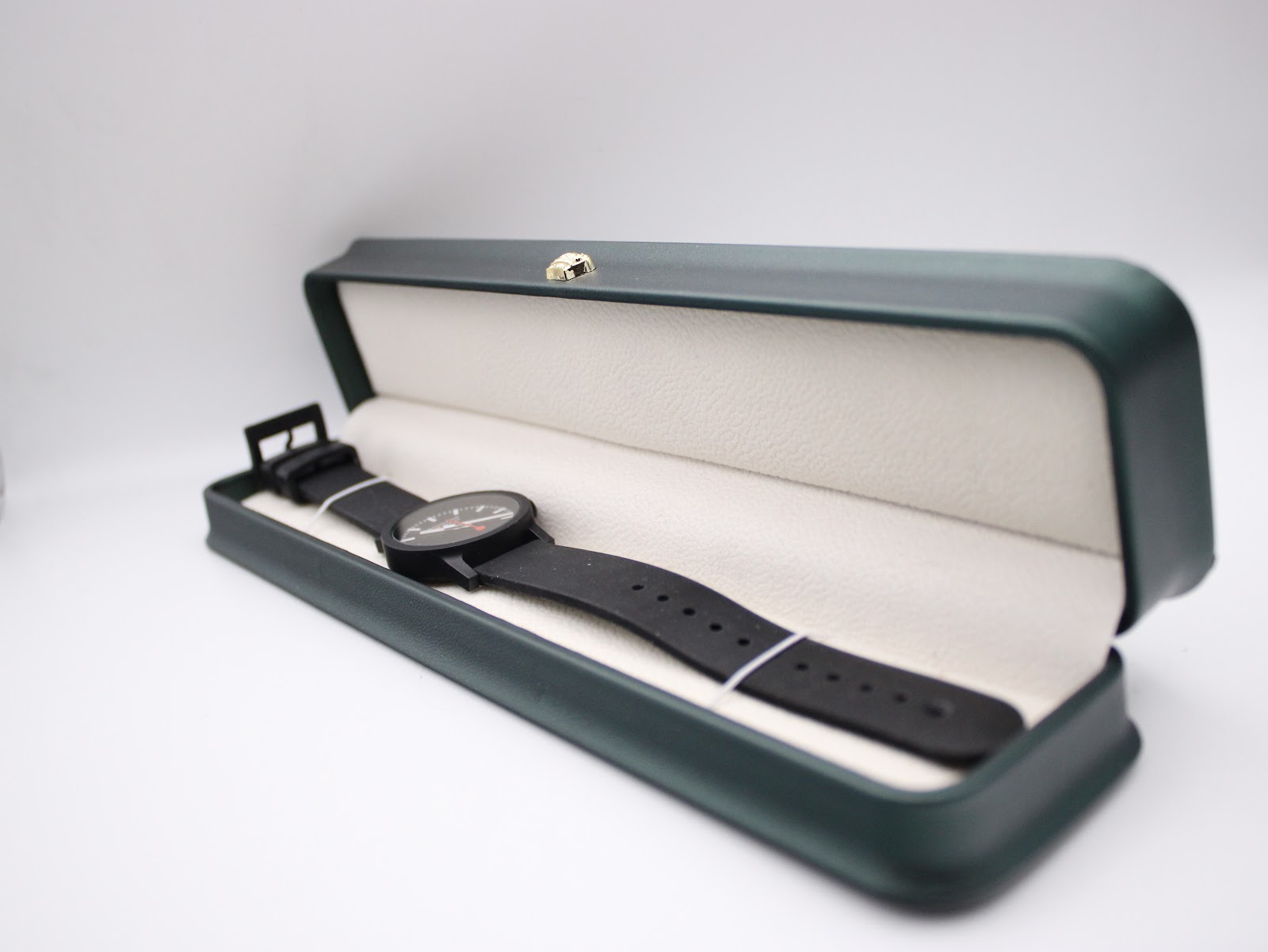 The Mondaine watch displayed inside a green watch box with a cream interior