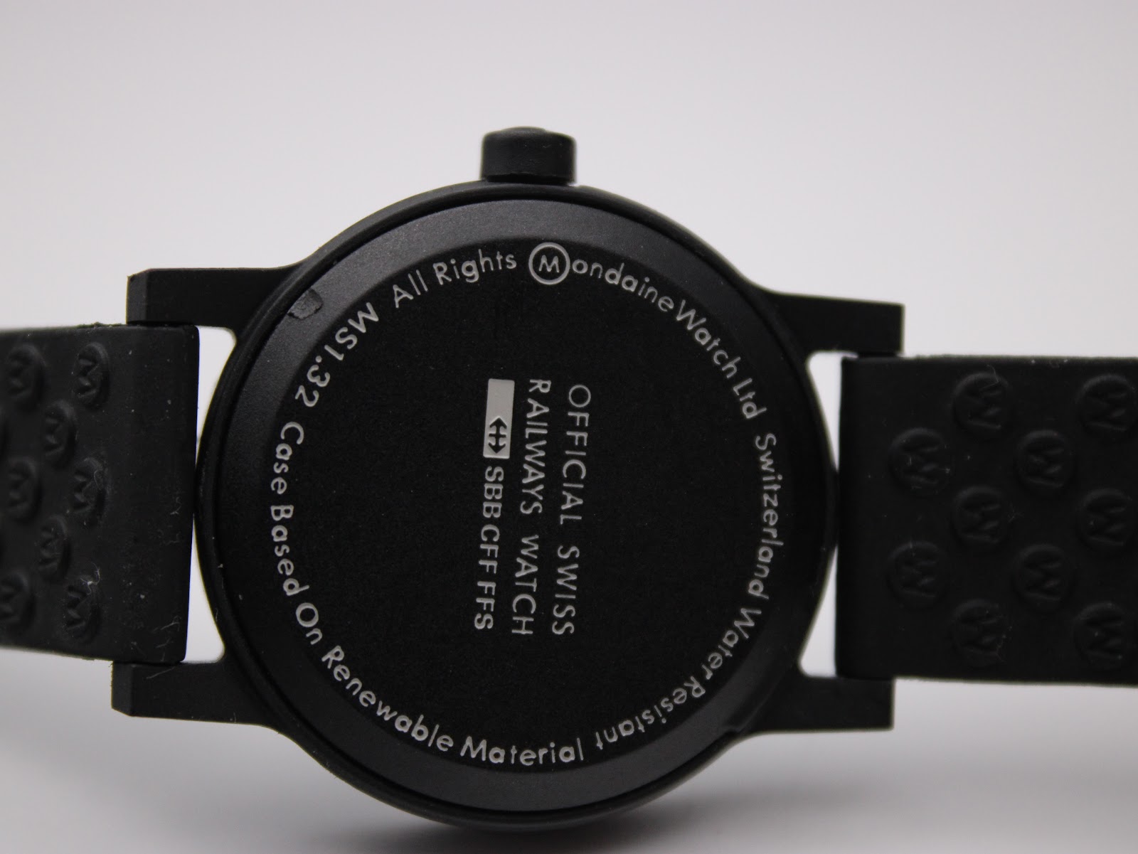 Close-up of the black case back, showing engraved text: Mondaine logo, Official Swiss Railways Watch, SBB CFF FFS, Case Based On Renewable Material