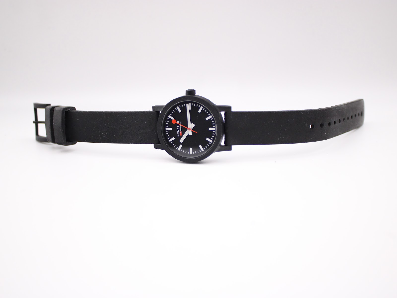 Top-down view of the Mondaine watch with its black rubber strap extended, showcasing the full length