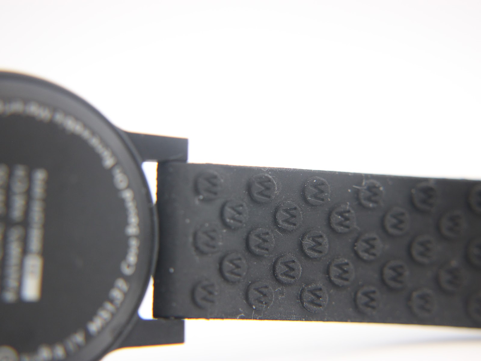 Close-up of the textured rubber strap, showing the repeated 'M' logo pattern near the case back