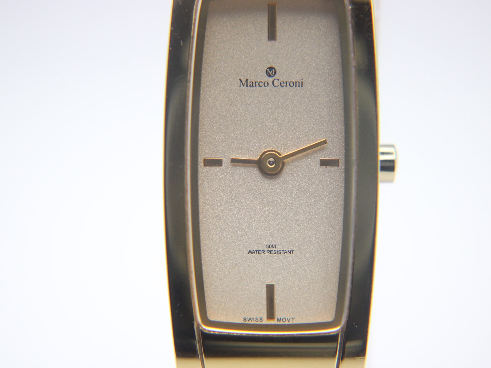 Close-up of the champagne dial, showing "Marco Ceroni", "50M Water Resistant", and "Swiss Movt" text with simple baton indices.