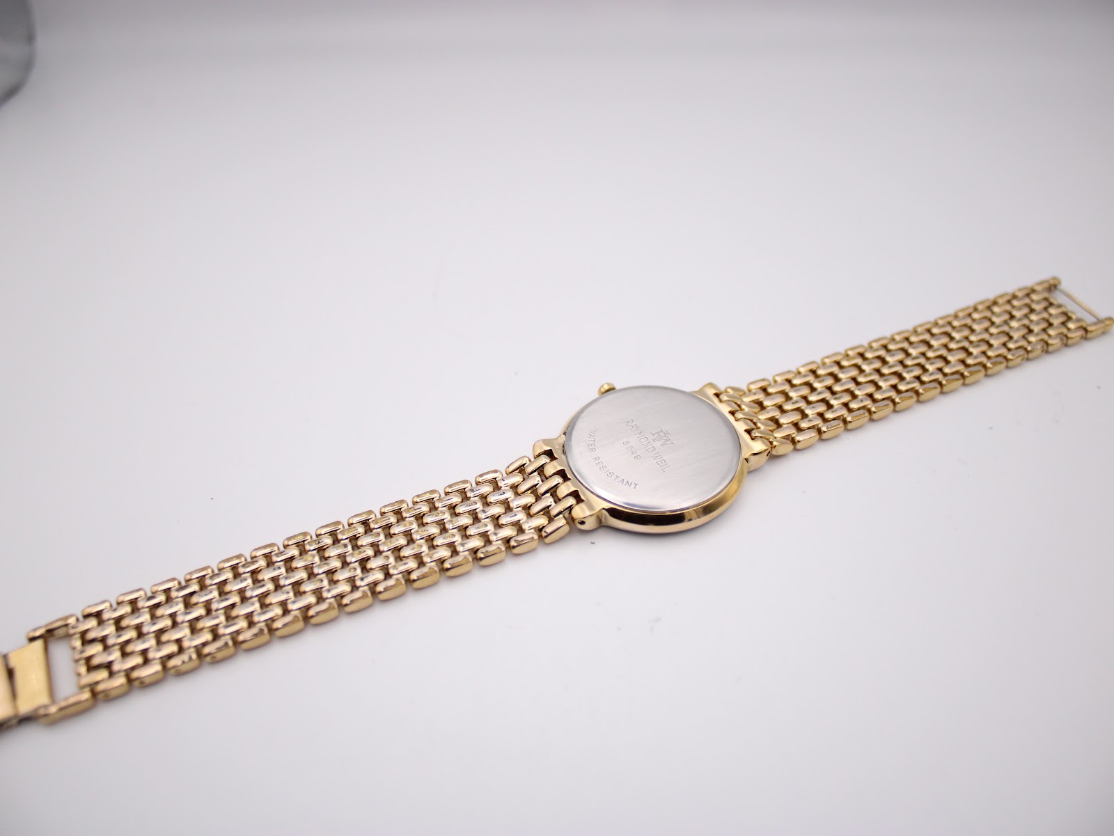 Full view of the watch from the back, showing the case back and the entire length of the gold and silver tone bracelet.