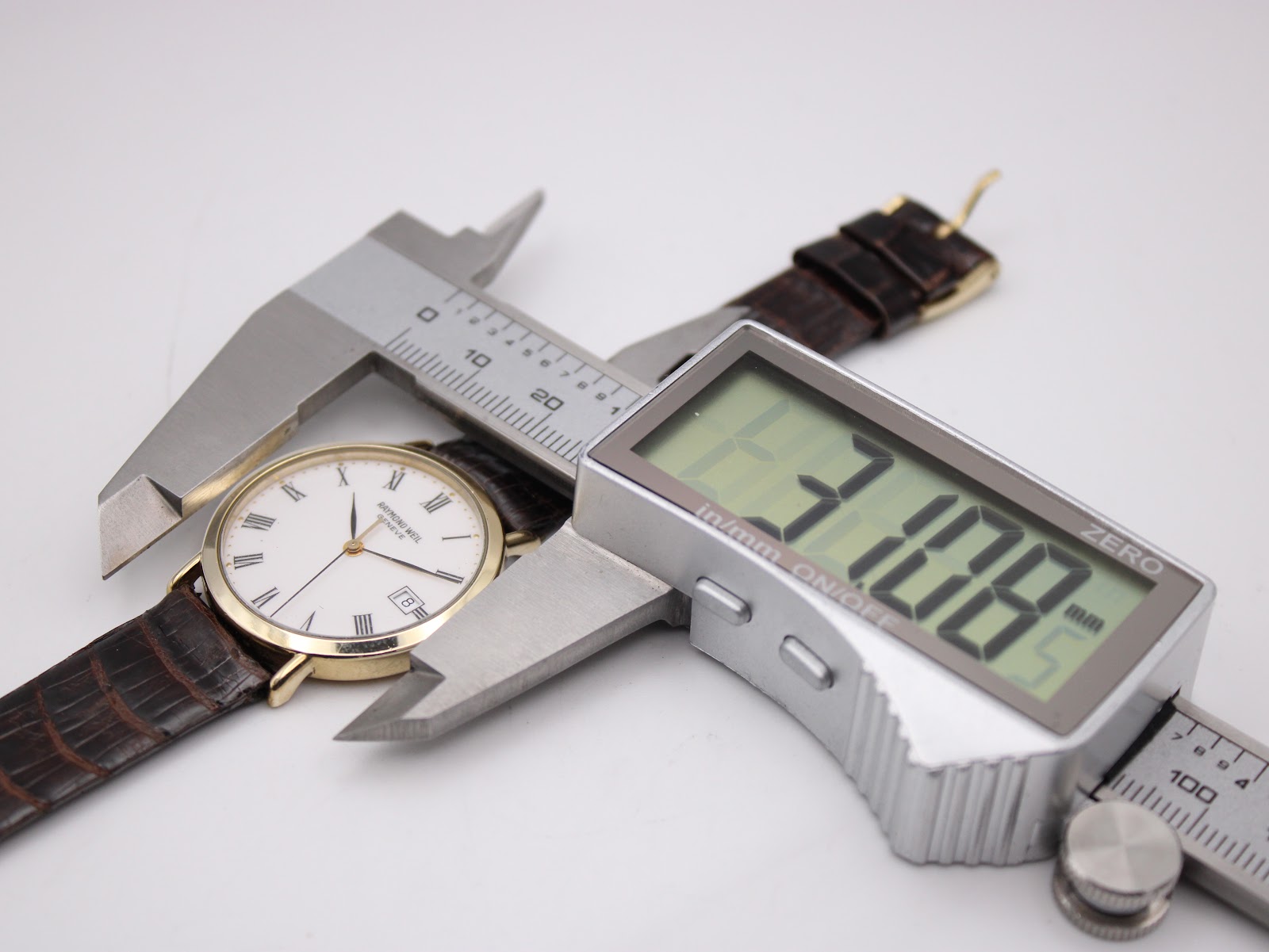 Close-up of the Raymond Weil watch being measured by a digital caliper, showing a case diameter of 31.08mm.