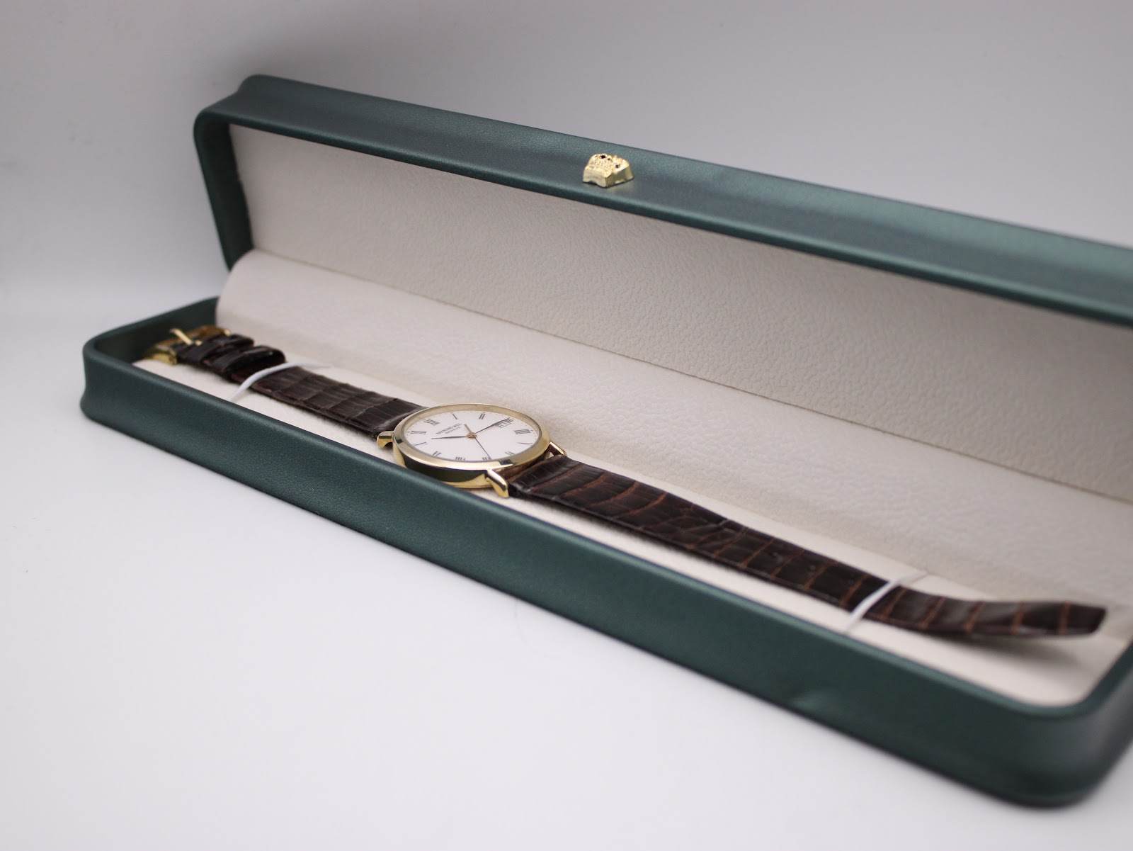 The Raymond Weil Geneve watch presented inside a dark green, white-lined watch gift box.