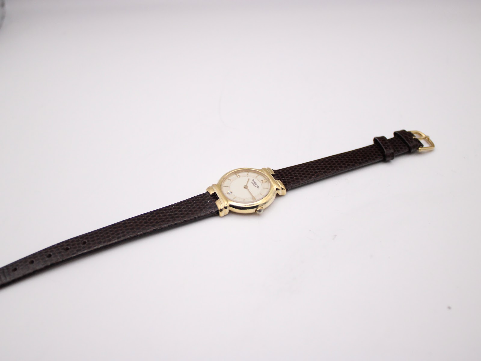 Full length view of the Raymond Weil watch with its dark brown lizard-style leather strap unbuckled on a white background.