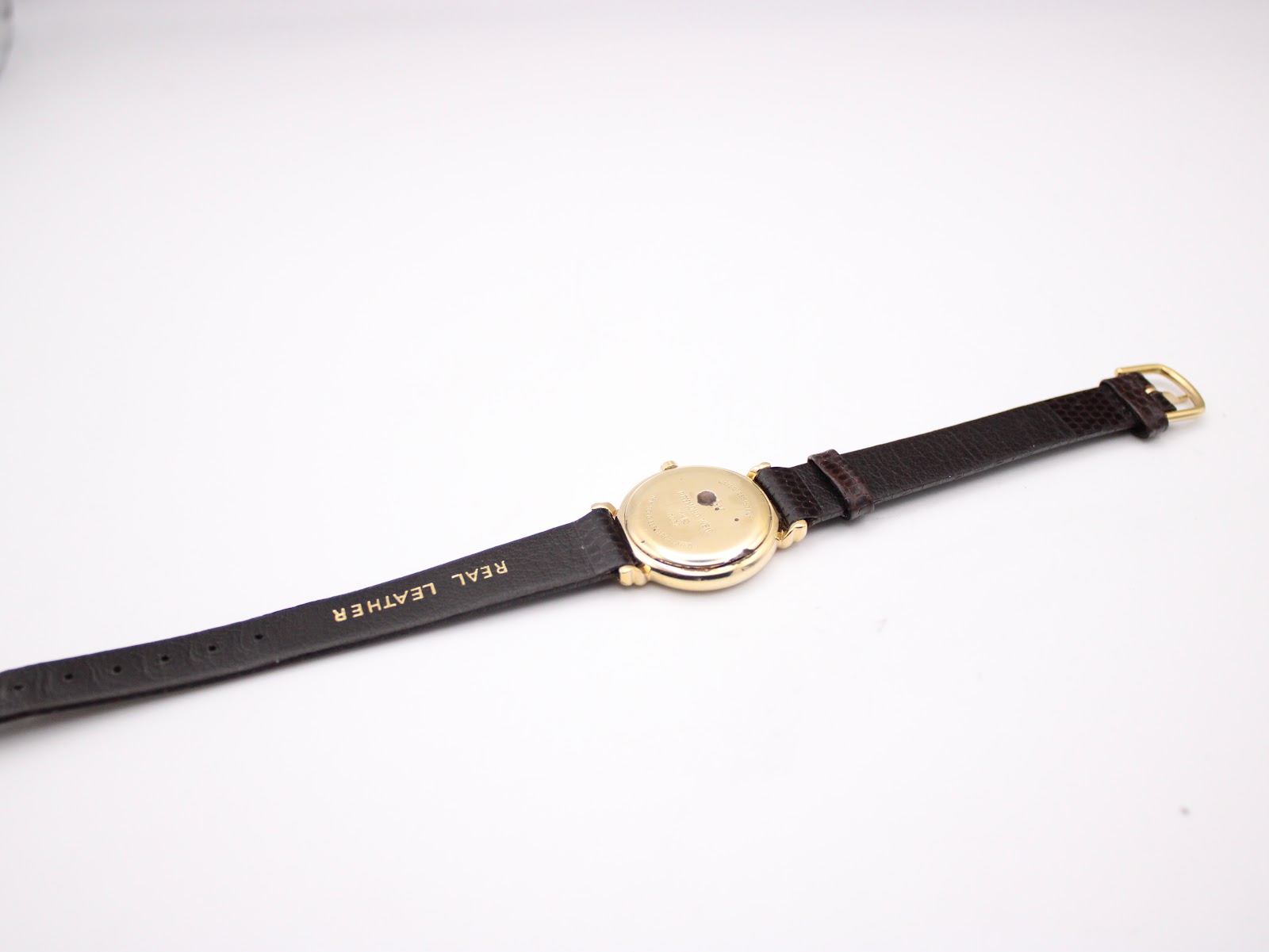 Back view of the watch and strap, showing the underside of the strap with 'REAL LEATHER' text and the case back.
