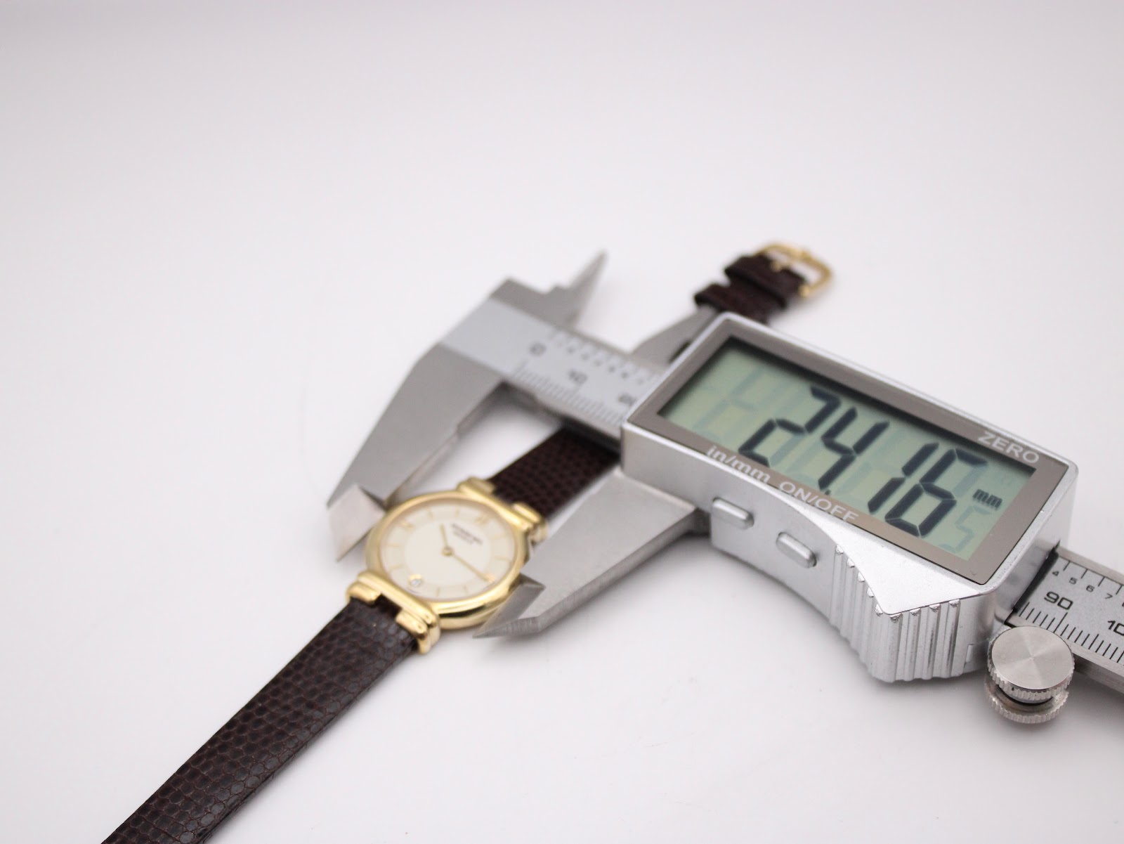 Digital caliper measuring the case diameter of the Raymond Weil watch, displaying an exact measurement of 24.16mm.