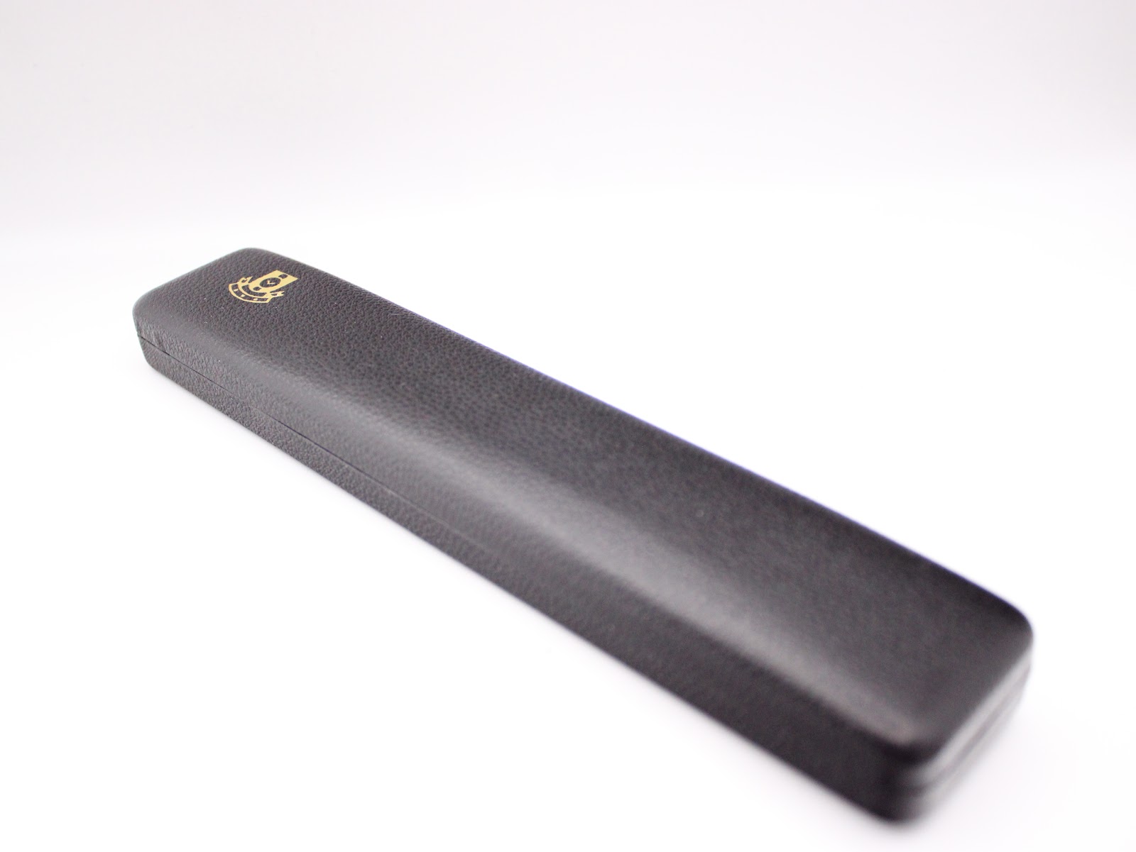 Exterior view of the closed dark grey textured presentation box with a gold logo.