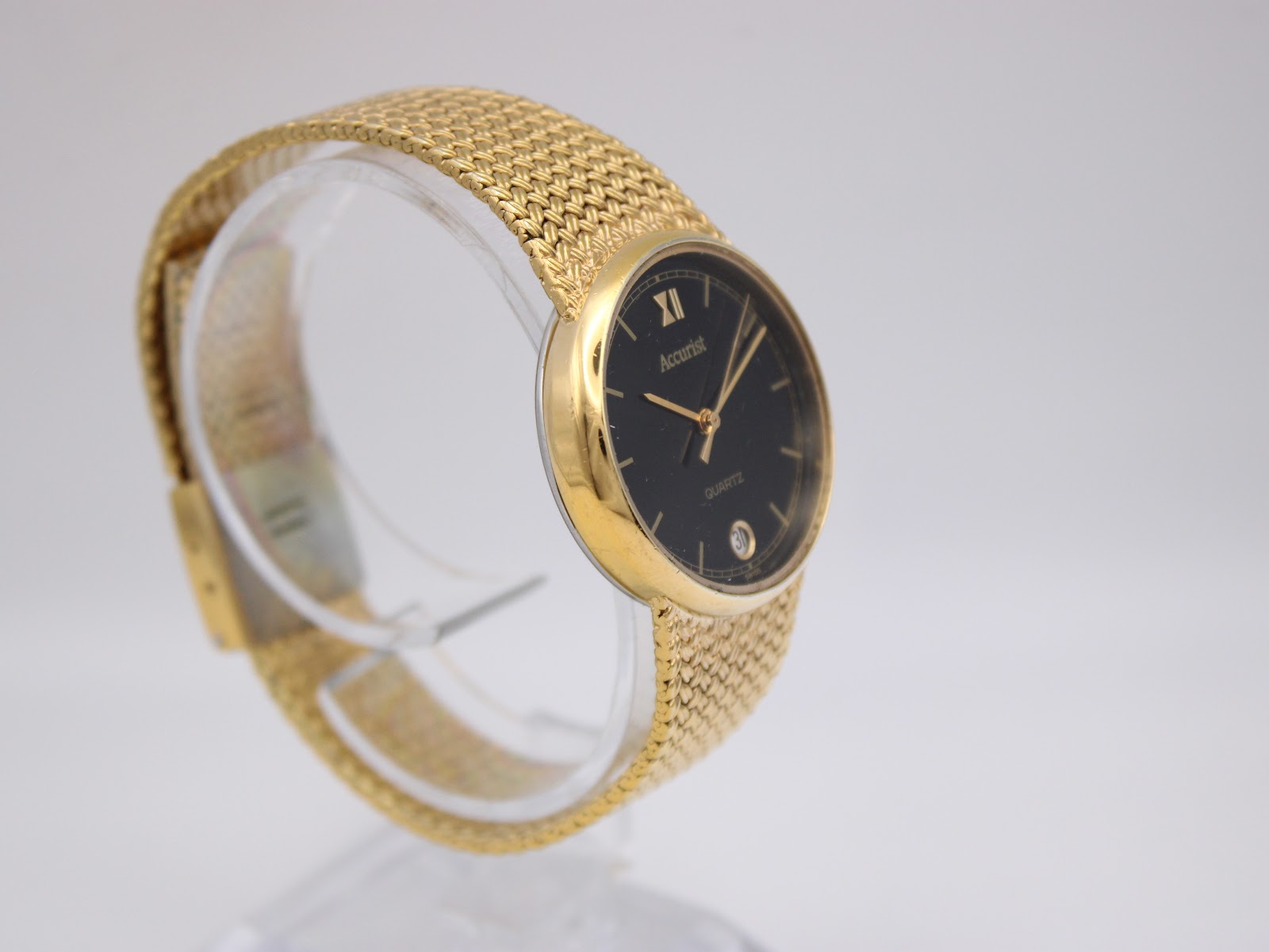 Angled view of the Accurist watch on a clear display stand, showing the case profile and black dial.