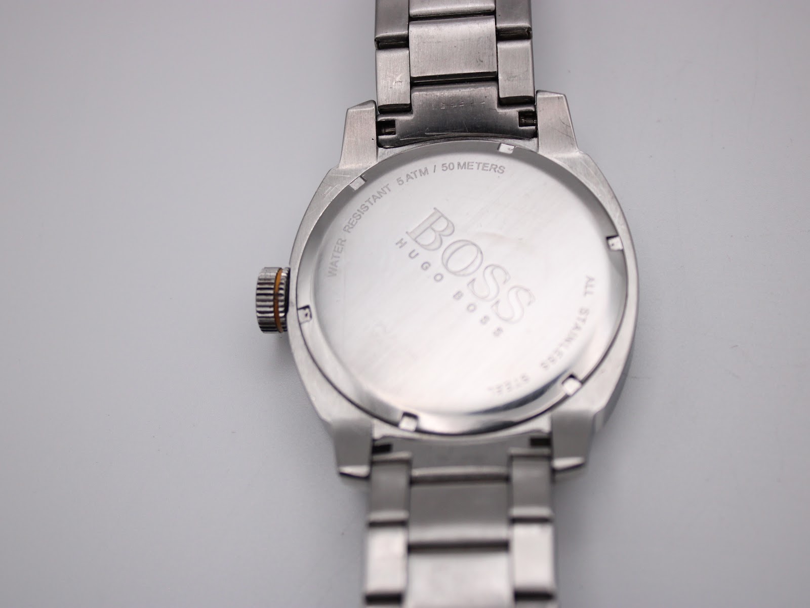 Close-up of the stainless steel case back of the Hugo Boss watch, engraved with "BOSS HUGO BOSS", "WATER RESISTANT 5 ATM / 50 METERS", and "ALL STAINLESS STEEL".