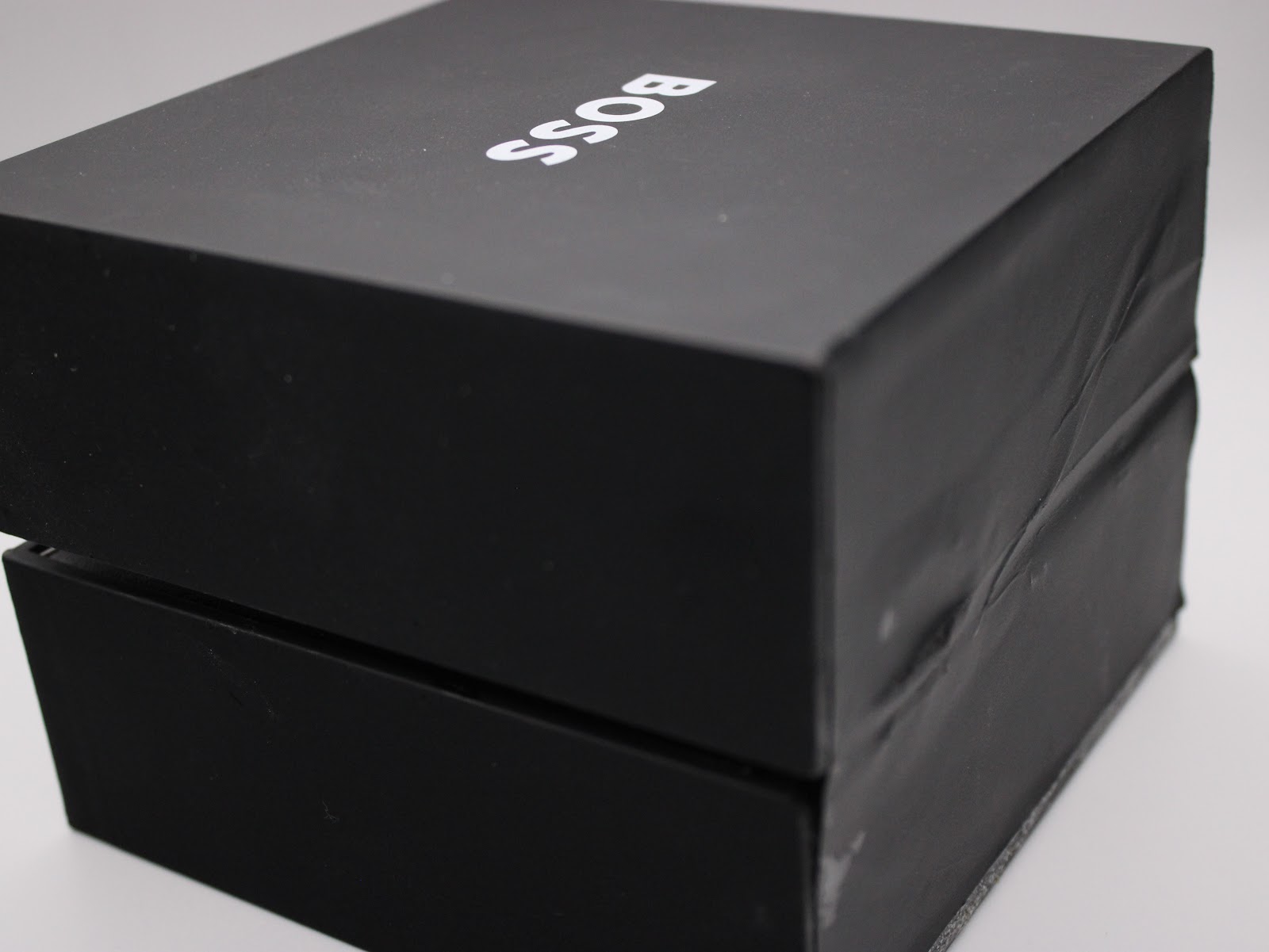 Top-down view of the black Hugo Boss presentation box with "BOSS" logo, showing some wear on the box exterior.