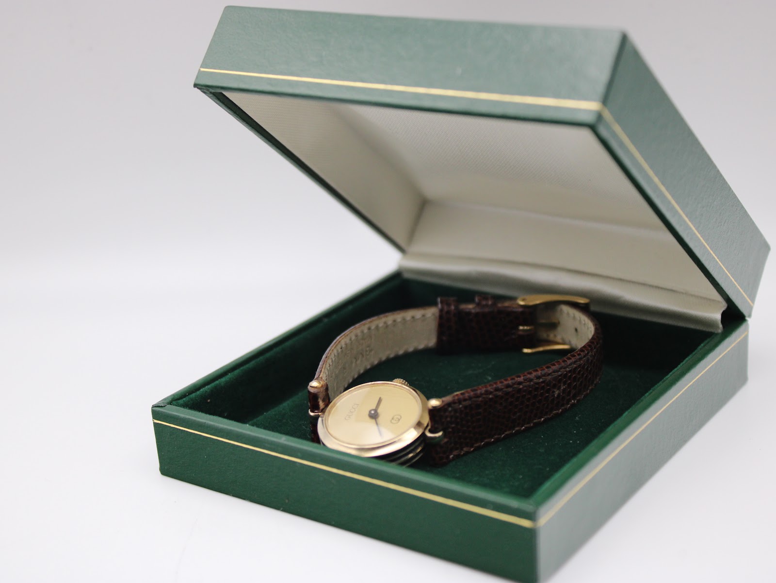The Gucci 2000L watch resting open in a green non-original presentation box, showcasing the overall elegant presentation.