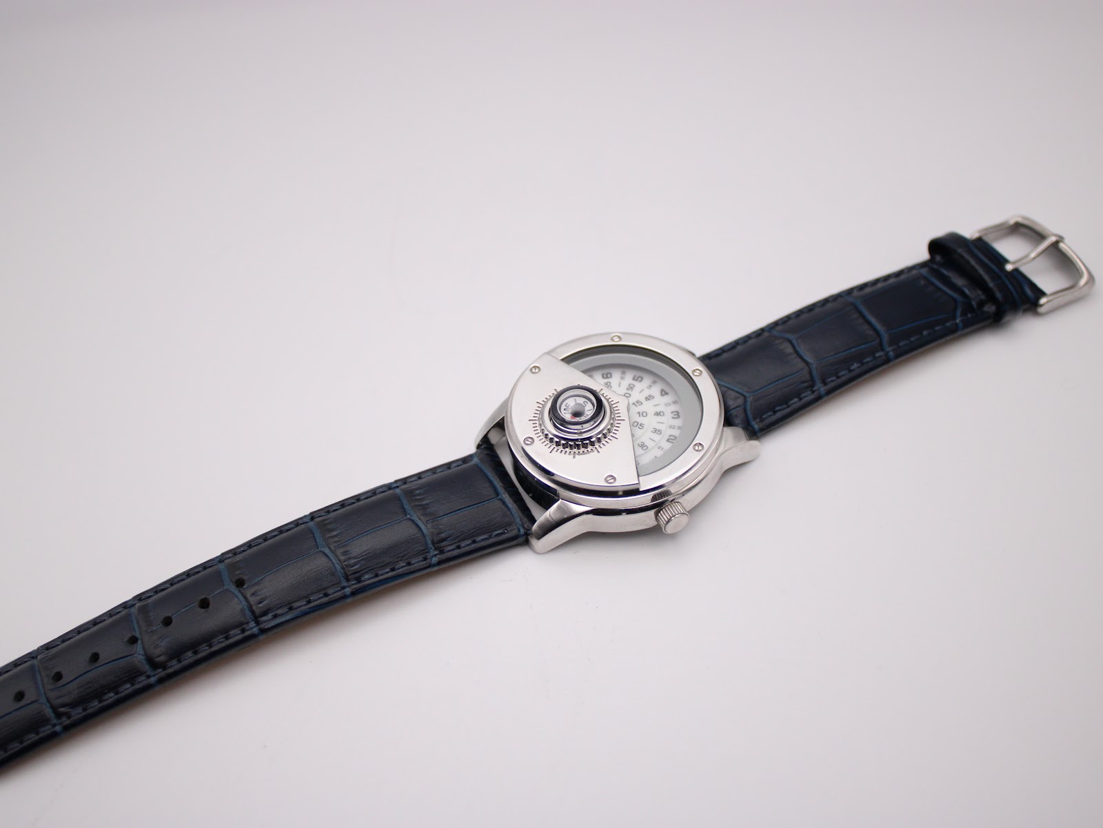 Overhead view of the Avon watch with the navy blue leather strap fully extended, showing the dial and buckle.