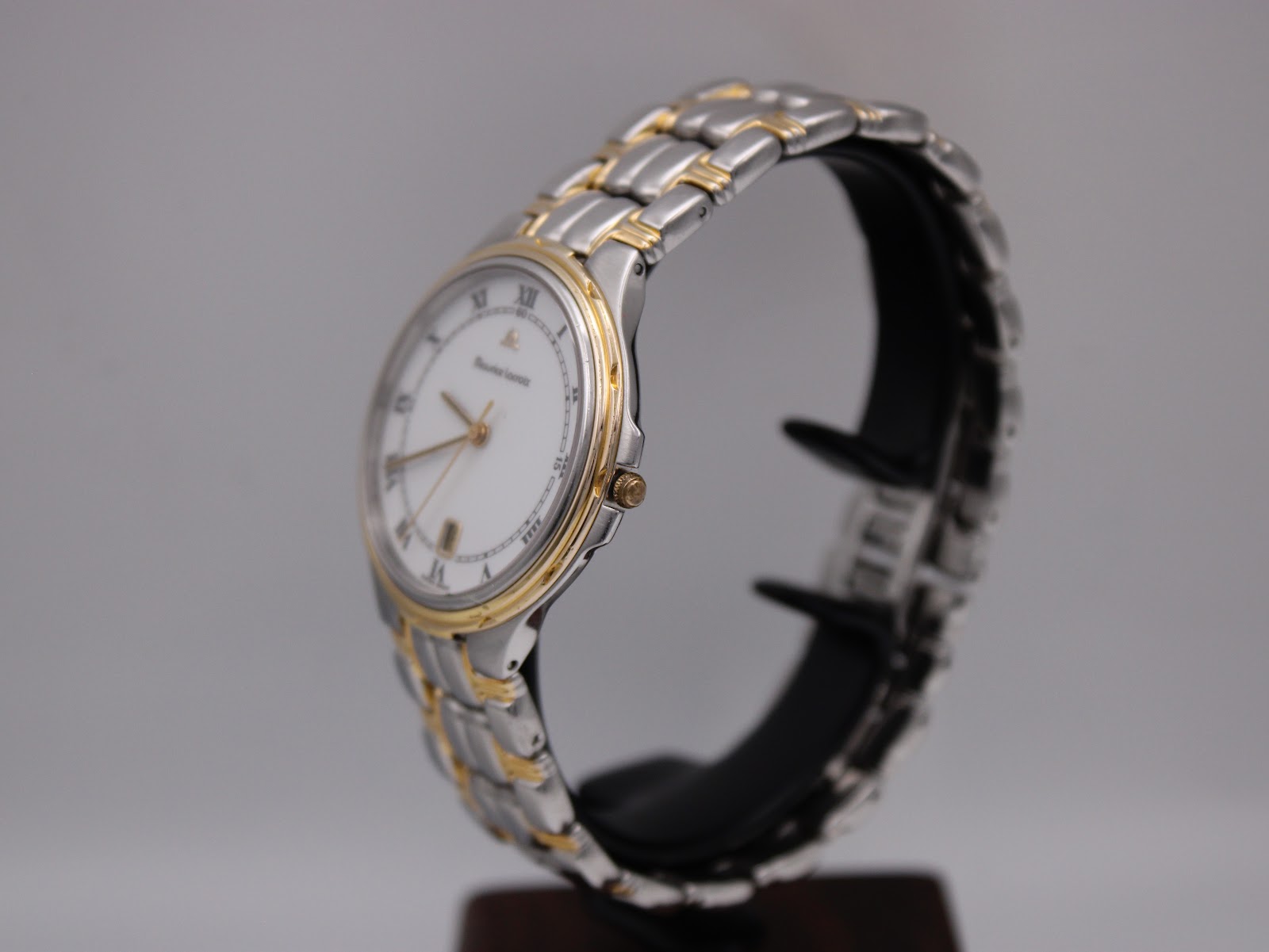 Side view of the Maurice Lacroix watch on a stand, showing the two-tone bracelet and gold-plated bezel.