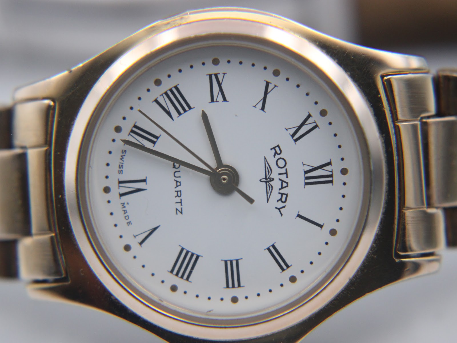 Detailed close-up of the white dial with clear black Roman numerals, a minute track, and "Rotary Quartz Swiss Made" text.