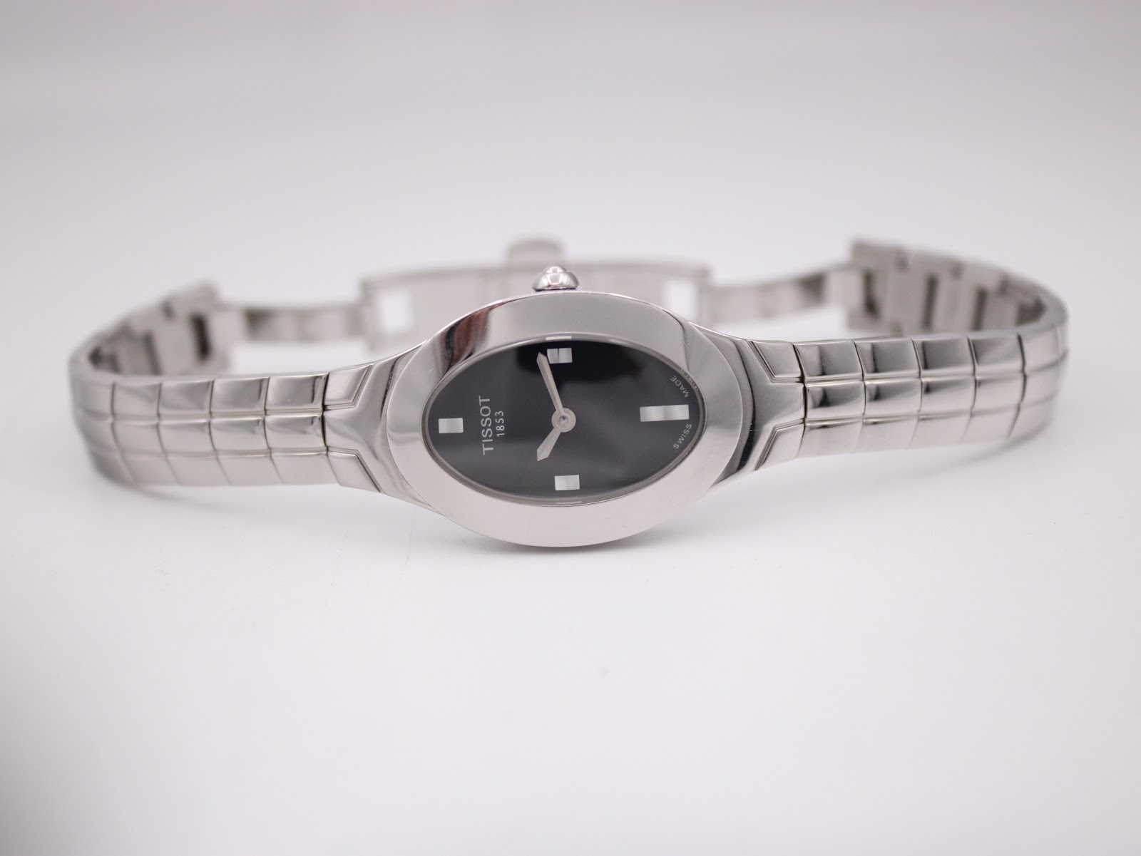 Full front view of the Tissot L720 watch laid flat, displaying the black oval dial and integrated stainless steel bracelet.