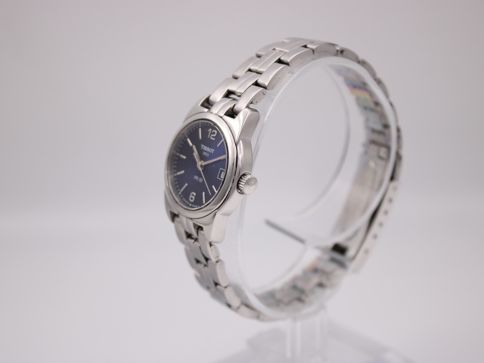 Angled side view of the Tissot PR 50 watch on a display stand, highlighting the case shape and bracelet links.