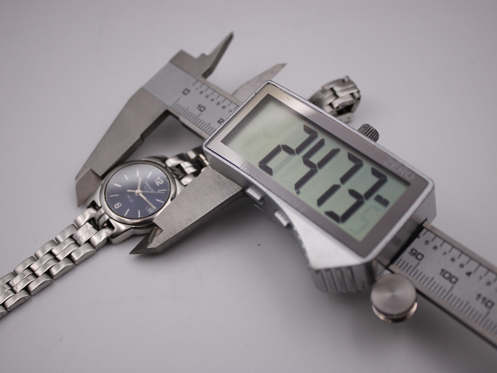 Digital caliper measuring the case diameter of the Tissot PR 50 watch, showing a precise reading of 24.73mm.