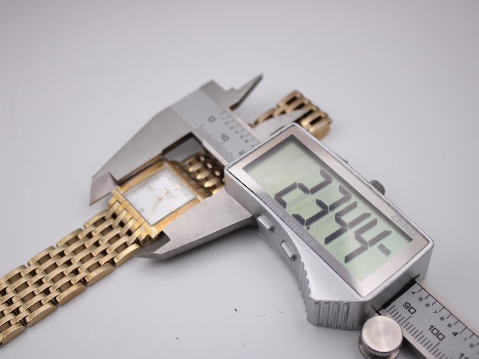 Digital caliper measuring the width of the Tissot L910 watch case, displaying a reading of 23.34mm.