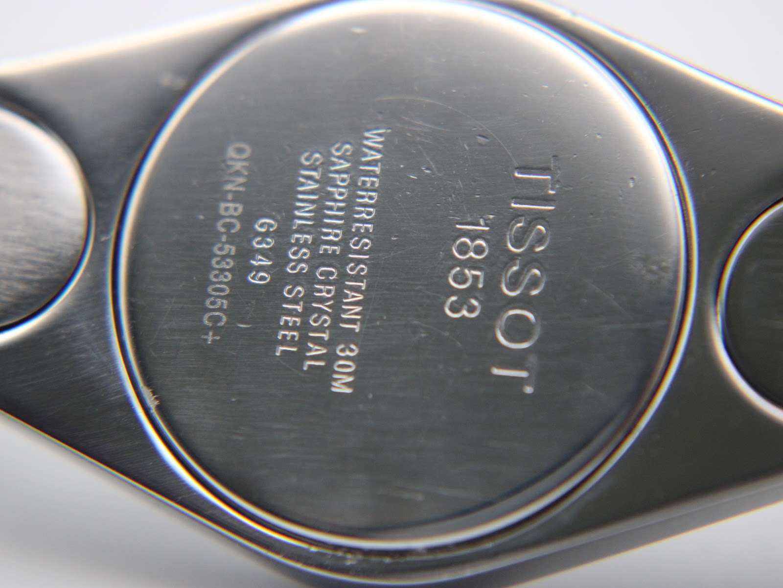 Close-up of the watch's case back, engraved with "TISSOT 1853", "WATERRESISTANT 30M", "SAPPHIRE CRYSTAL", "STAINLESS STEEL", and "G349".