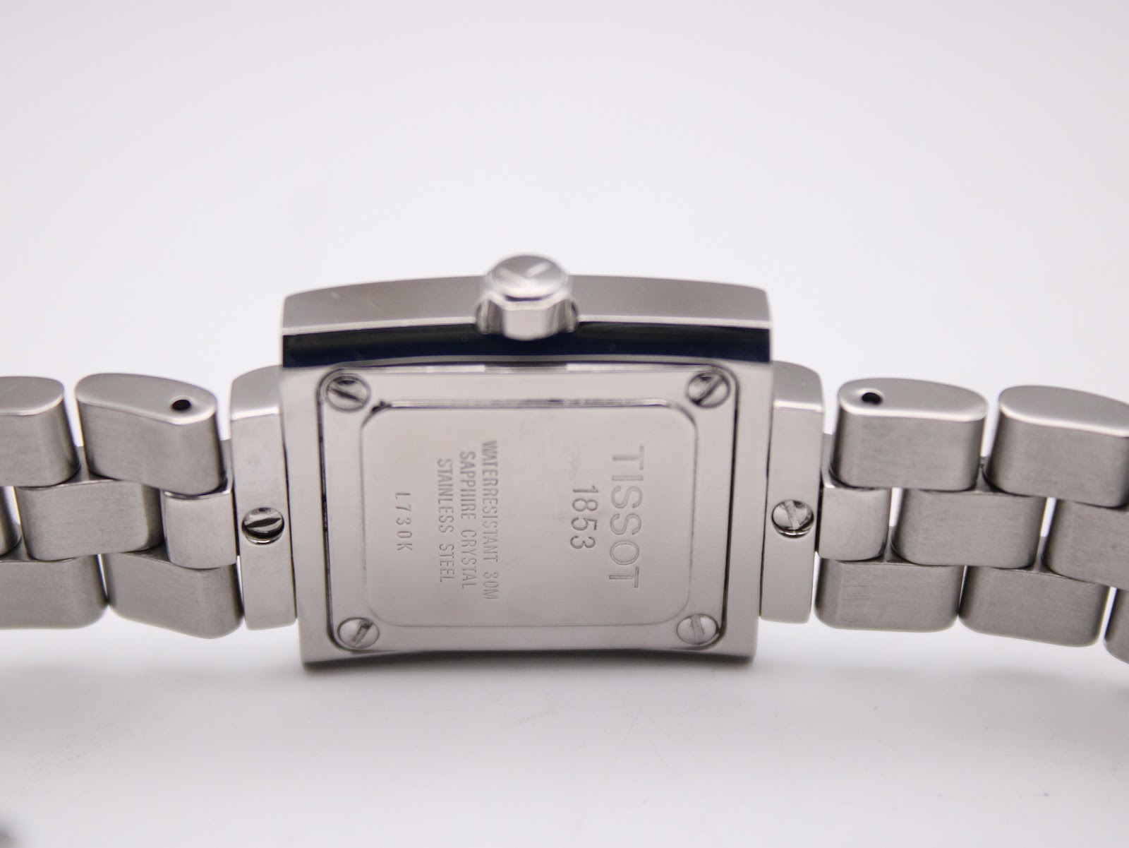 Close-up of the polished stainless steel case back, showing 'Tissot 1853', 'Waterresistant 30m', 'Sapphire Crystal', 'Stainless Steel', and 'L730K' engravings.
