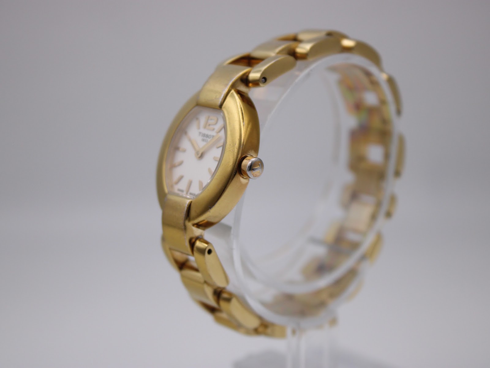 Angled side view of the gold-tone Tissot G332 watch showing the crown and the integrated bracelet design.