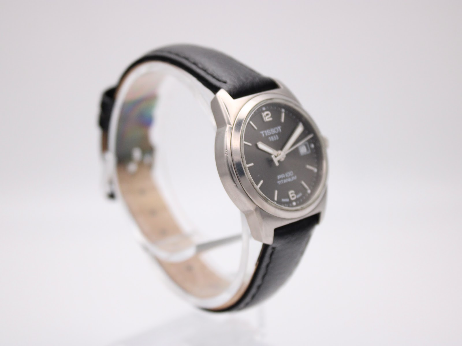 Left side profile of the Tissot watch showing the brushed titanium case on a display stand.