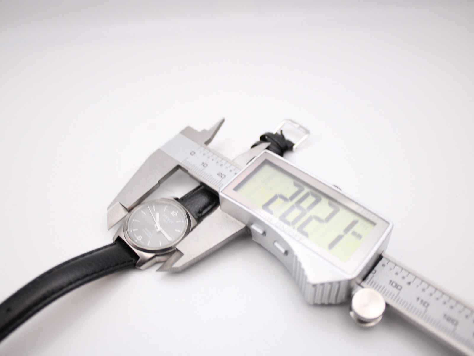 Digital caliper measuring the case diameter of the Tissot watch at precisely 28.21mm.