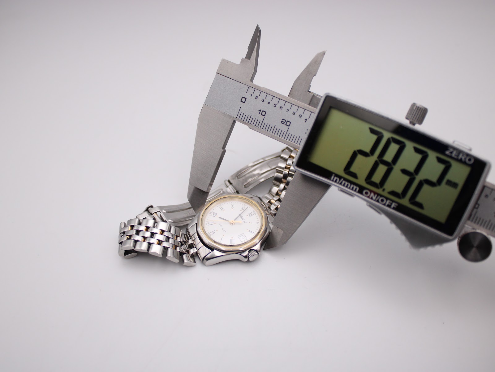 Close-up of a digital caliper measuring the watch's bezel diameter, displaying a precise reading of 28.32mm.