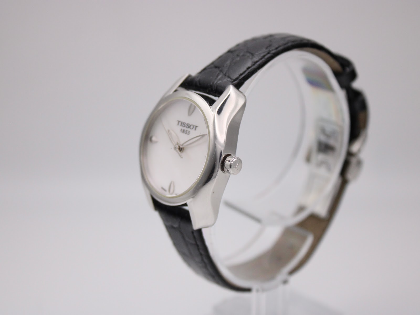 Side profile view of the Tissot T023210A watch on a clear display stand, highlighting the sculpted silver case and crown.