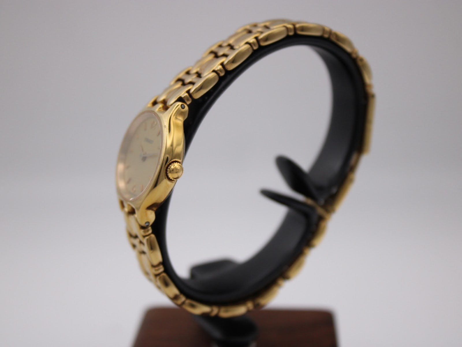 Side profile of the gold Tissot watch, highlighting the crown and the elegant curve of the case and bracelet links.
